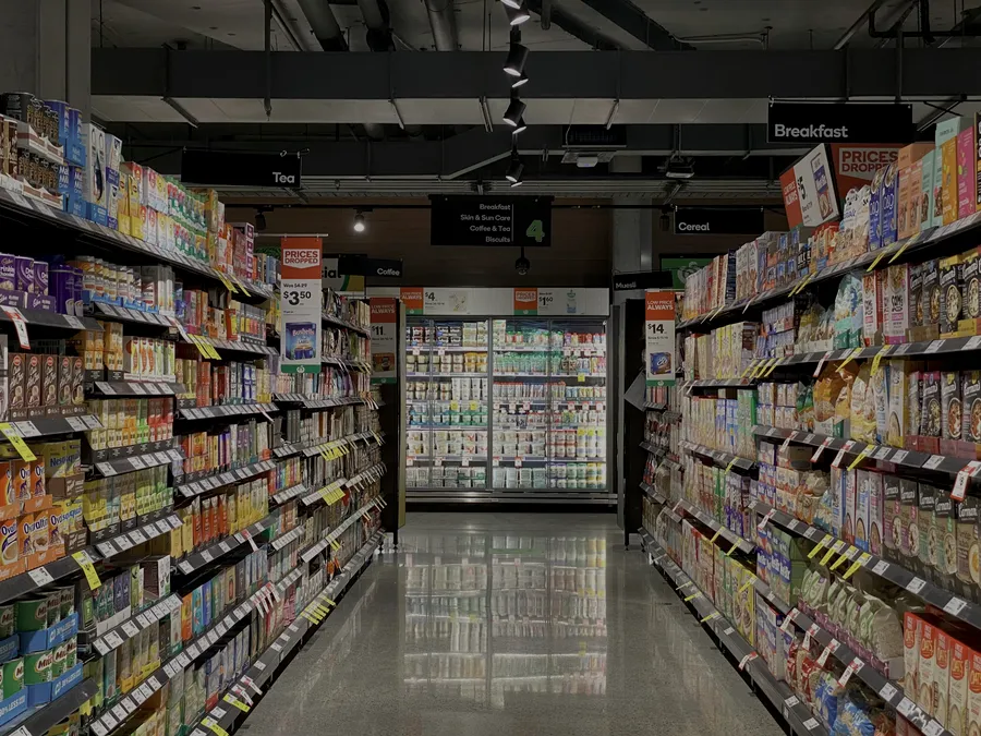 A grocery aisle stocked with packaged food and drinks on tall shelving
